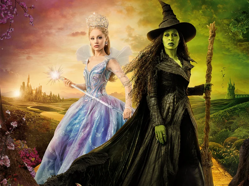 Duas personagens de contos de fadas, as protagonistas do filme Wicked, posam contra um fundo de paisagem fantástica. A Bruxa Boa (Glinda), à esquerda, veste um vestido azul e rosa pastel e usa uma coroa, enquanto a Bruxa Má (Elphaba), à direita, tem a pele verde, veste roupas pretas escuras e segura uma vassoura.